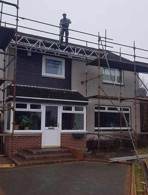 A DSY Roofing & Building Contractors roofer on scaffolding working on a house roof in Stirling